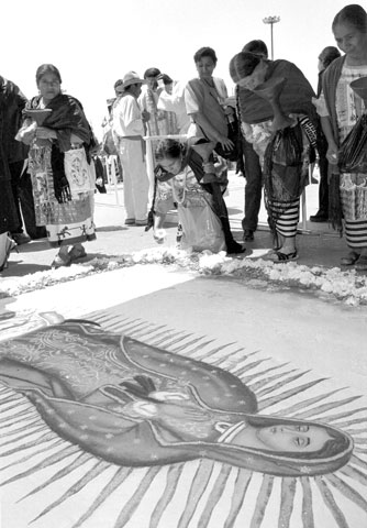 Mujeres mexicanas recogen flores de un mural de la Virgen de Guadalupe