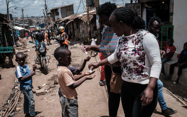Unas voluntarias de la ONG Shining Hope for Communities proporciona desinfectante de manos a unos niños de Nairobi (Kenia)