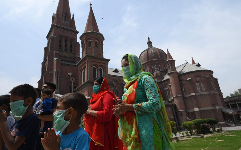 Una familia cristiana reza frente a la catedral de Lahore al retomarse el culto tras las restricciones por el COVID-19