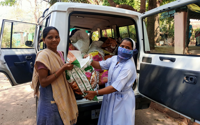 La hermana Jostna entrega una bolsa con alimentos a Deepa de camino a la comunidad tribal de Mas-hachapada (India), durante la pandemia