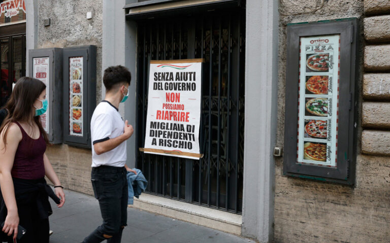 Dos jóvenes observan el cartel de una pizzería cerrada en Roma (Italia)