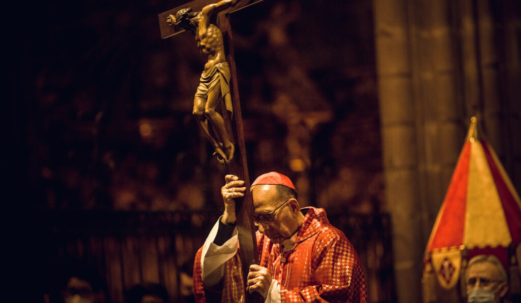 El cardenal Omella porta la cruz durante el rezo del vía crucis en Barcelona