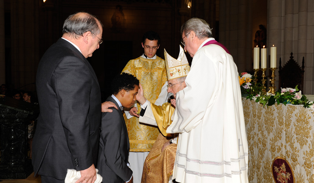 El cardenal Antonio María Rouco administra a un joven el sacramento de la Confirmación