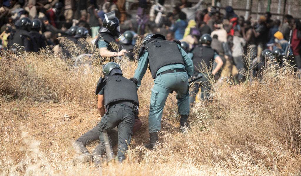 Un migrante es detenido por agentes de policía después de cruzar la valla de Melilla el 24 de junio de 2022