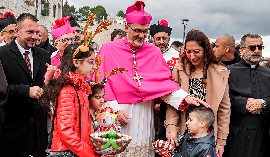 Pierbattista Pizzaballa junto a unos niños miembros del movimiento scout en el exterior de la iglesia de la Natividad de Belén, el 24 de diciembre de 2021