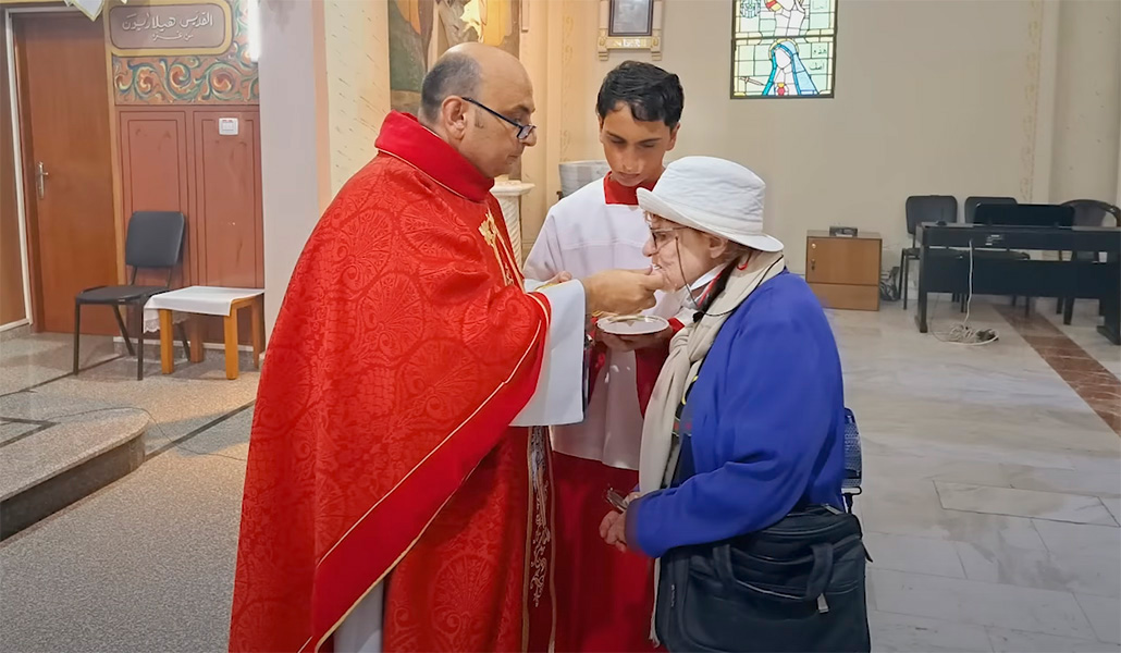 Anciana comulga en la parroquia de Gaza