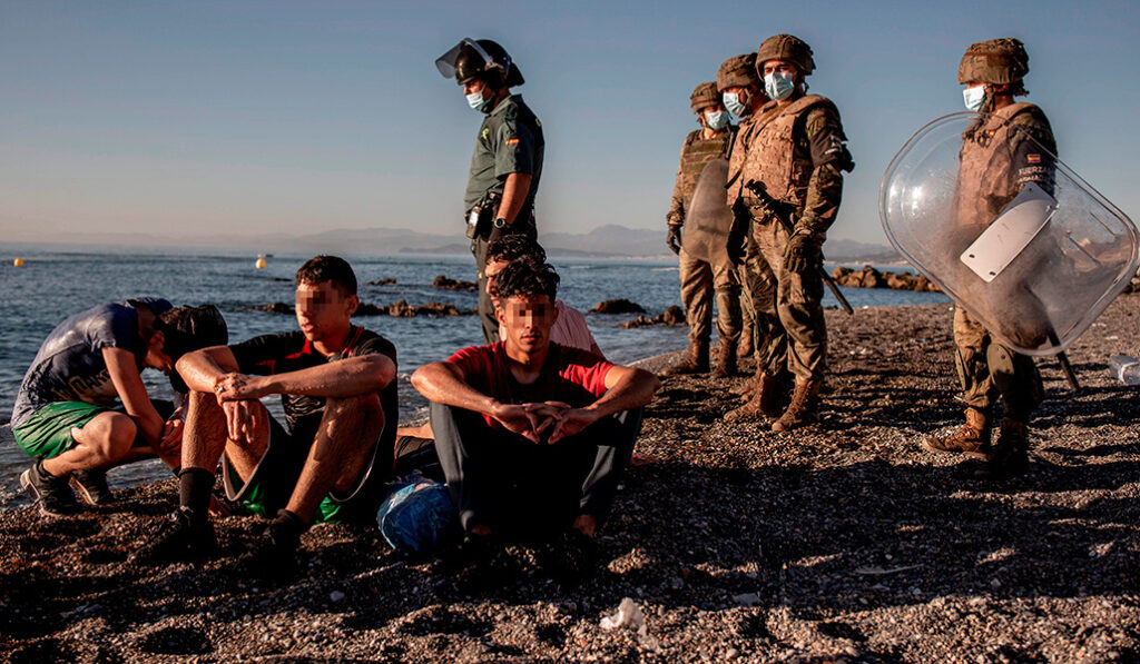 Miembros del Ejército junto a un grupo de menores en la playa del Tarajal, en Ceuta