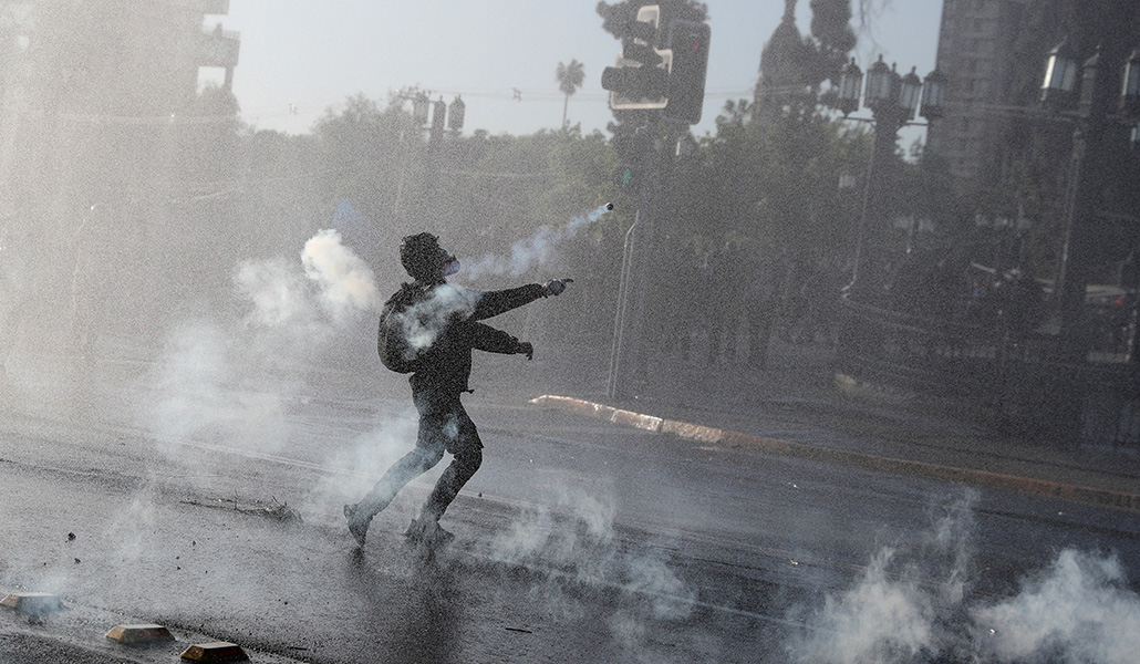 Un manifestante lanza una lata de gas lacrimógeno durante una manifestación en el cuarto aniversario de las protestas y disturbios que sacudieron al país en 2019, en Santiago de Chile, el 18 de octubre de 2023