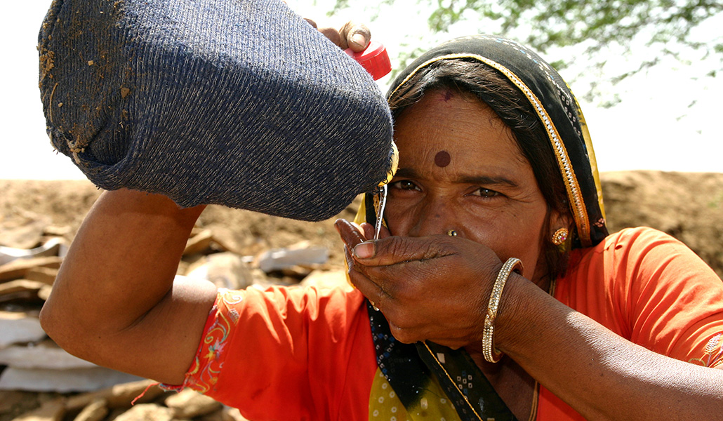 Una mujer bebe agua en un mercado en India