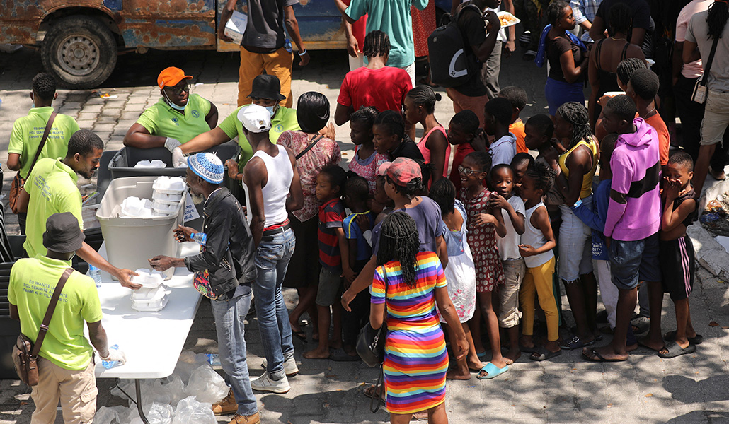Personas que huyeron de la violencia reciben comidas en una escuela que se utiliza como refugio en Puerto Príncipe (Haití)