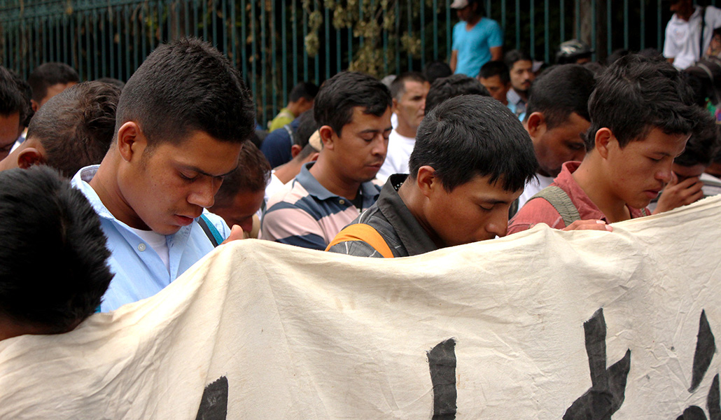 Vía crucis migrante. Participantes sostienen una pancarta mientras rezan frente al complejo de Los Pinos, en Ciudad de México