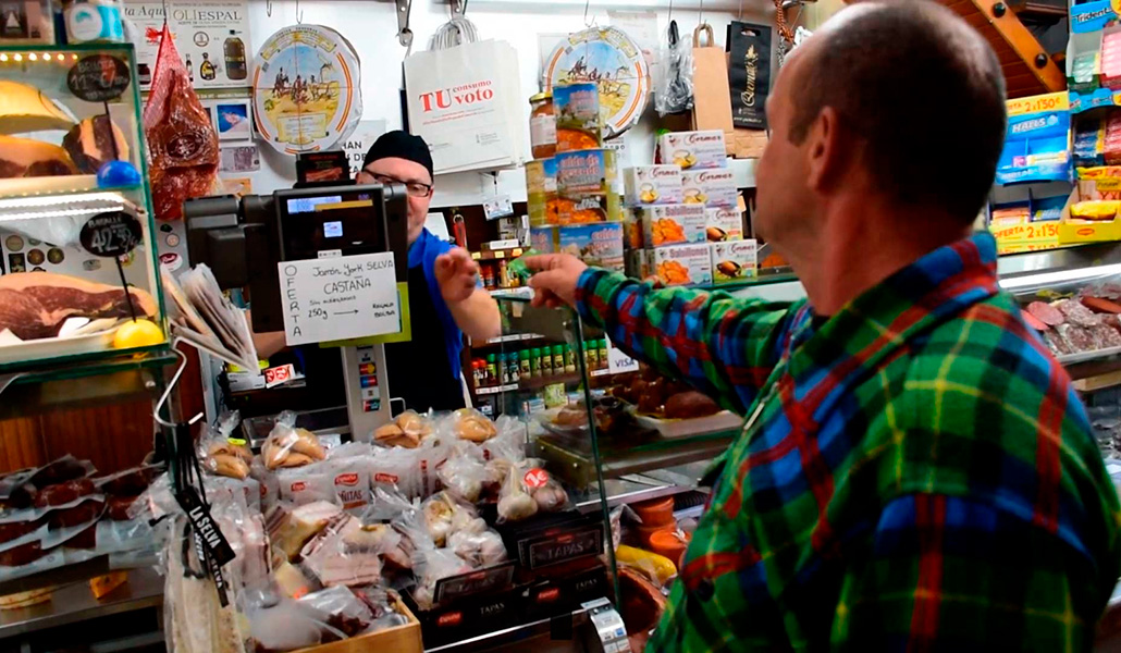Una persona hace la compra en una tienda con la tarjeta monedero facilitada por Cáritas Valencia