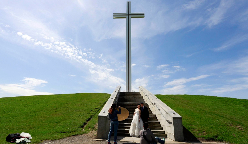 Una pareja de recién casados bajo la cruz papal del parque Phoenix, en Dublín