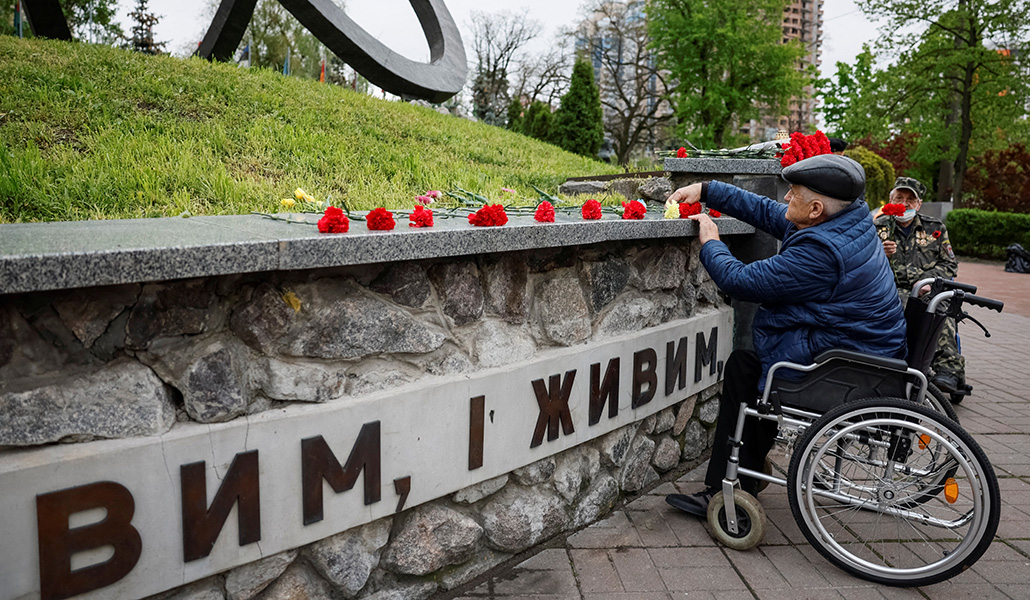 Unos hombres depositan flores en un monumento a los bomberos y trabajadores que murieron tras la explosión de un reactor en la central nuclear de Chernóbil, mientras asisten a una ceremonia de conmemoración del 38º aniversario del desastre de Chernóbil, en Kiev, Ucrania, el 26 de abril de 2024