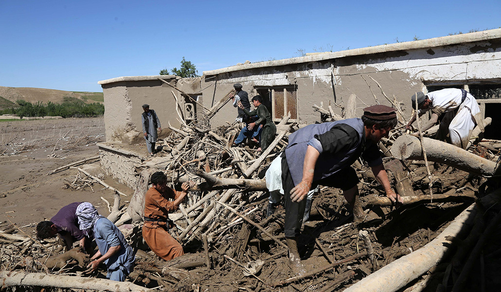 Unas personas retiran las ramas tras las inundaciones en Borka (Afganistán)