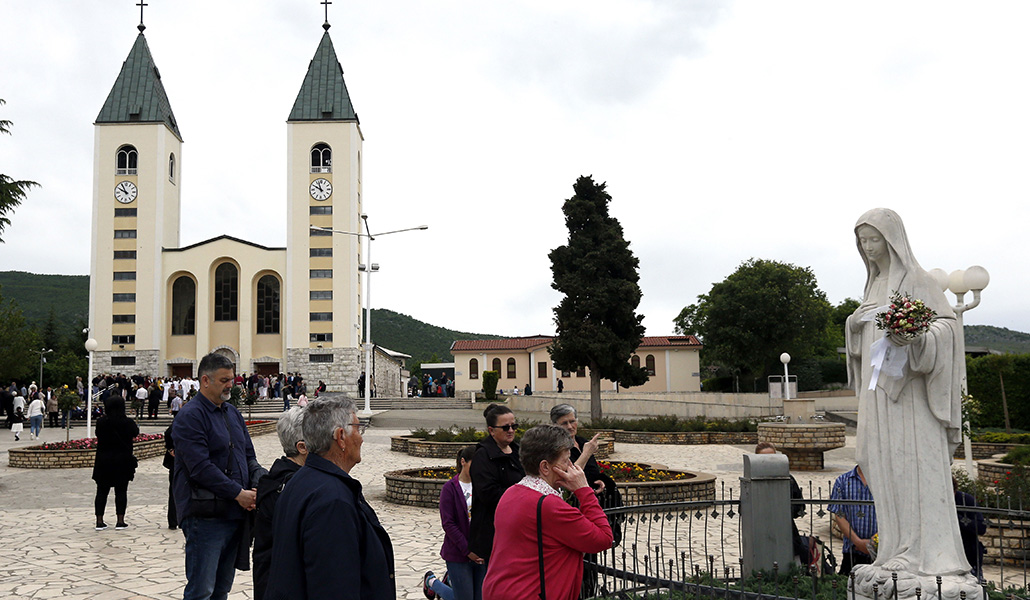 Peregrinos rezan ante una imagen de la Virgen fuera de la iglesia de Medjugorje, cuyas apariciones no se han reconocido aún como auténticas