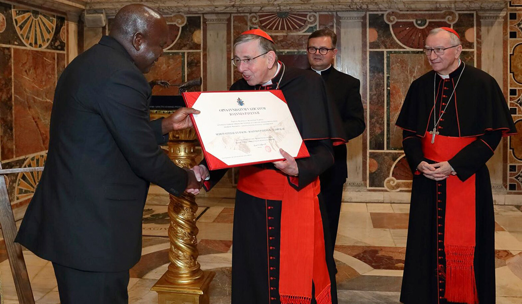 El padre Olobo Leonard recibe el premio de manos del presidente del comité de premios, el cardenal Kurt Koch, en el Vaticano