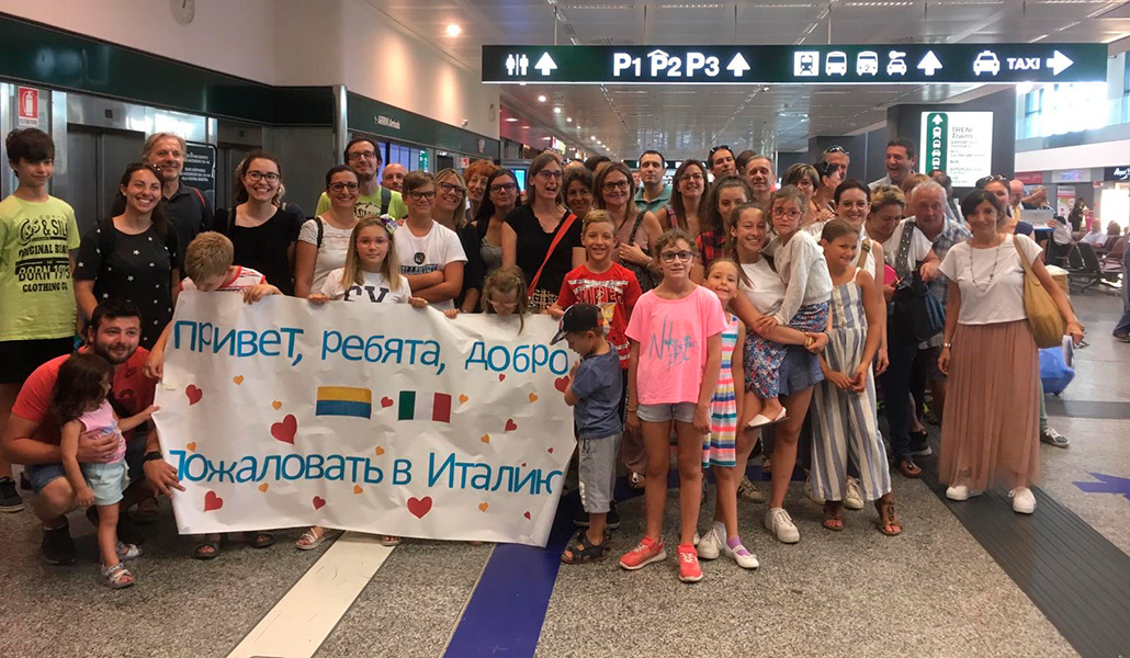 Las familias de acogida en el aeropuerto mientras reciben a los niños que pasarán en Italia el verano