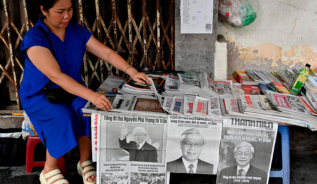 Una vendedora organiza unos periódicos que informan sobre la muerte de Nguyen Phu Trong, secretario general del Partido Comunista de Vietnam, en Hanoi