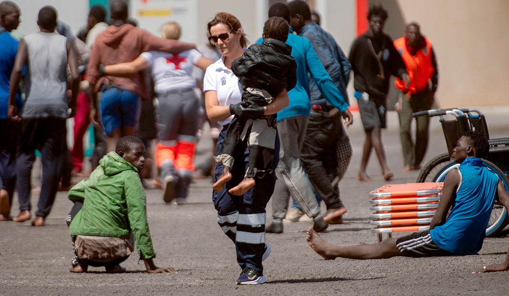 Un miembro de los servicios de emergencia lleva a un niño pequeño, parte de un grupo de 175 inmigrantes que llegaron a bordo de un barco, al puerto de Restinga en la isla canaria de El Hierro el 18 de agosto de 2024