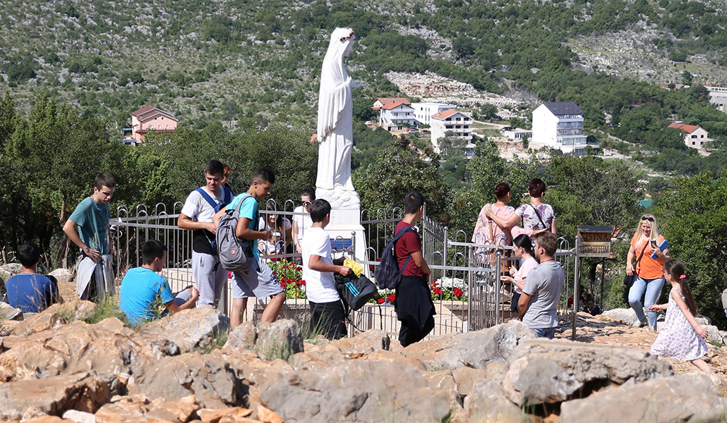 Jóvenes peregrinos rodean una estatua de María en la Colina de las Apariciones en Medjugorje