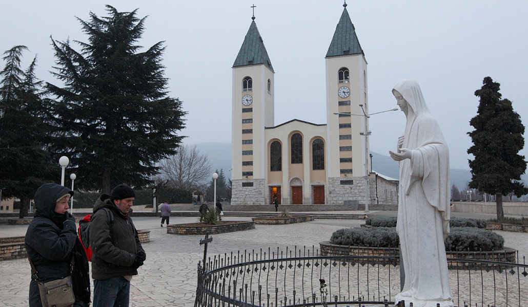 Dos hombres, rezando ante la imagen de la Virgen, situada en el exterior de la iglesia de Santiago, en Medjugorje, Bosnia-Herzegovina, 25 de febrero de 2011