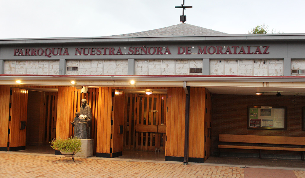 Fachada exterior del templo. La imagen de la Virgen sostiene entre sus manos una pequeña casa como las del barrio