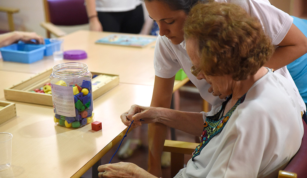 Una trabajadora ayuda a una anciana durante un taller en la estancia diurna para enfermos de Alzheimer en Sevilla