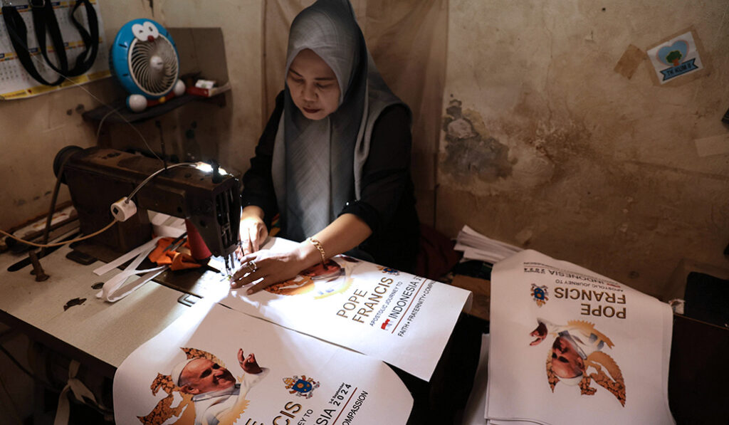 Una trabajadora musulmana cose bolsas con la imagen del Papa en Tangerang