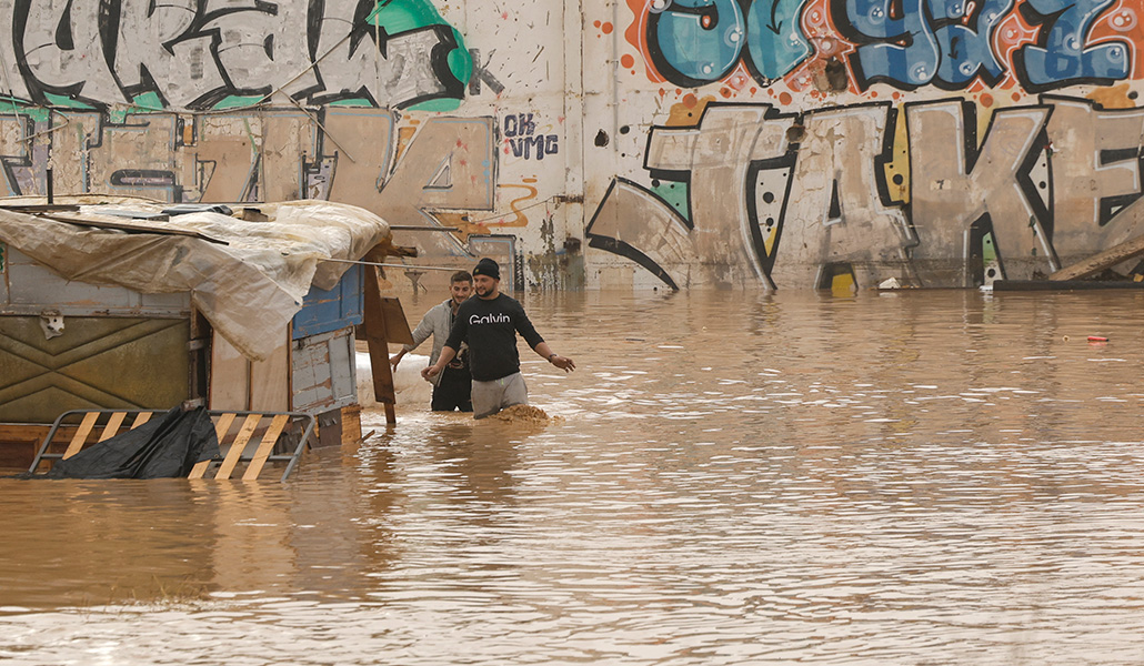 Dos personas caminan por un terreno de chabolas inundado junto a la V-30 a causa de las lluvias torrenciales en Valencia