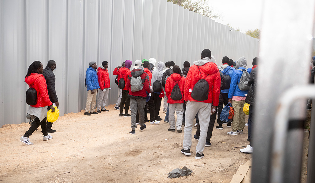 Migrantes frente al muro que cerca el acuartelamiento Primo de Rivera en Alcalá de Henares