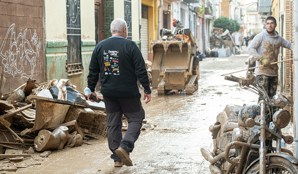 El párroco de Sedaví (de espaldas)supervisa las tareas de limpieza en las calles de la localidad