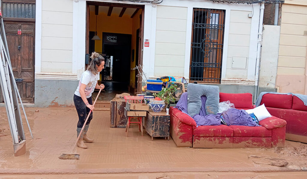 Una vecina limpia la acera al lado de su casa, muy cerca del templo de este barrio