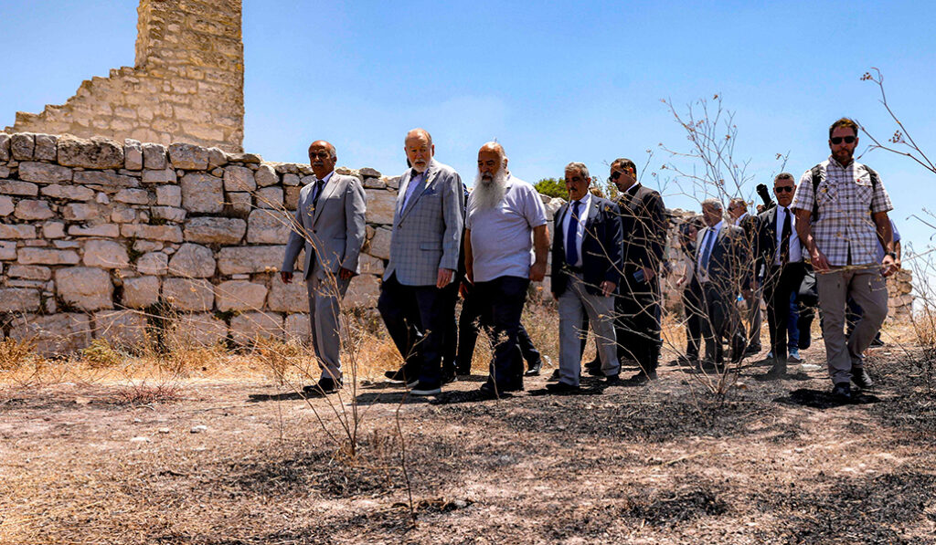 Huckabee (segundo por la izquierda) visita el terreno quemado el 7 de julio junto a la iglesia de San Jorge.