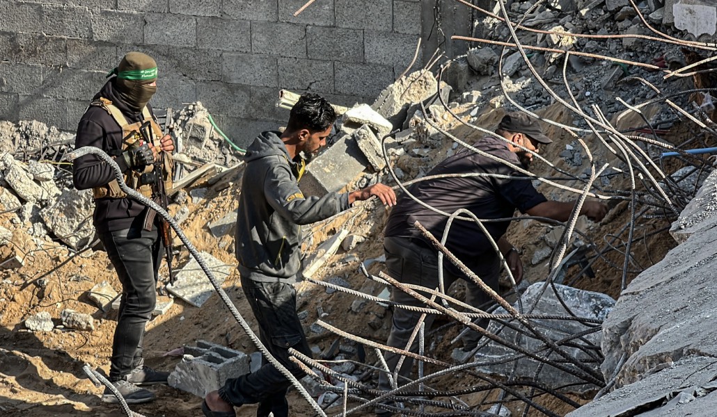 Miembros de un equipo egipcio y del brazo armado de Hamás buscan restos de rehenes israelíes en el campo de refugiados de Nuseirat, bombardeado por Israel en 2024