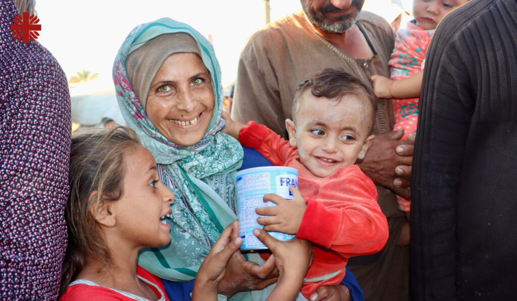 Una madre con sus dos hijos sonríe tras recibir un bote de leche infantil.