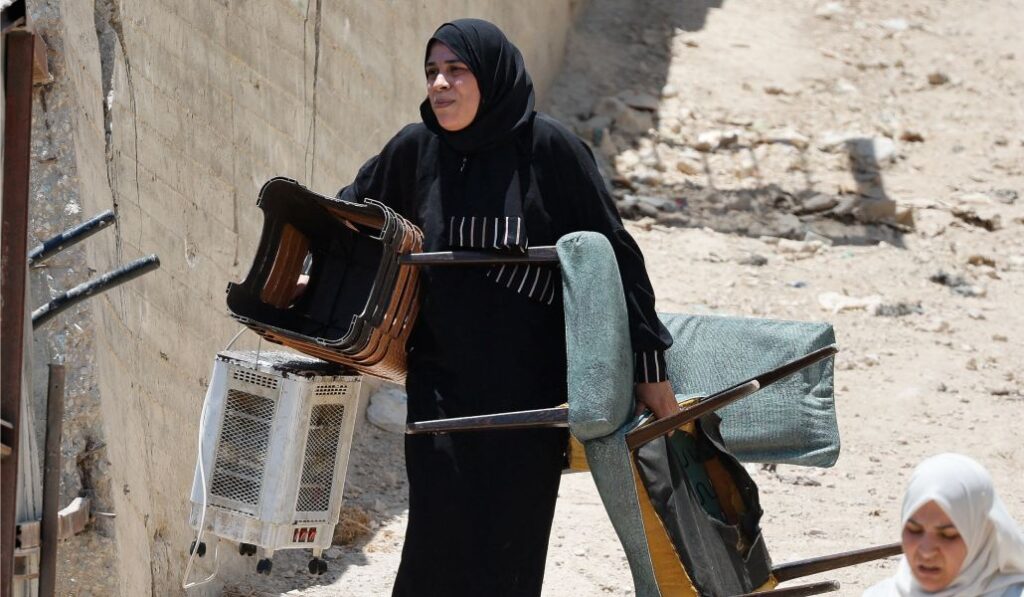 Una mujer palestina camina con sus pertenencias durante una operación militar de Israel en el campamento de Tulkarm, en Cisjordania