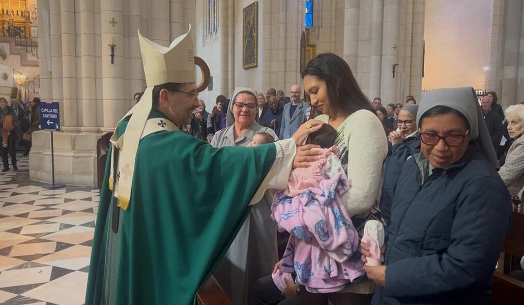 El cardenal Cobo bendice a un bebé durante la celebración. Foto: Cáritas Madrid.