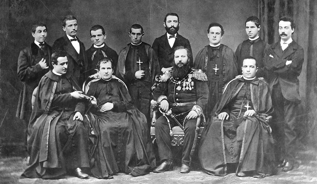 Foto de familia con el cónsul Gazzolo antes de partir. Don Bosco entrega a Cagliero las constituciones.