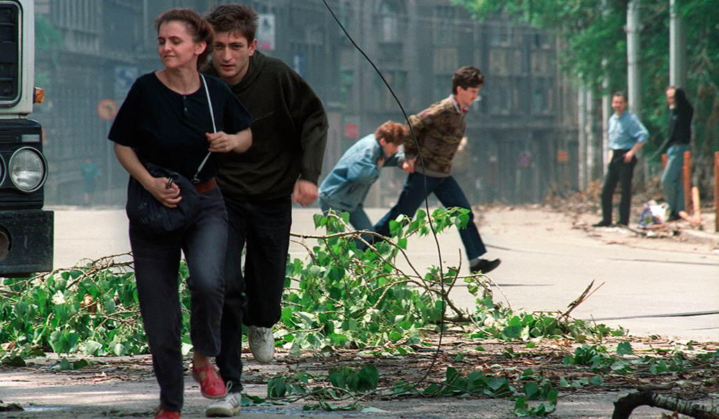 Residentes de Sarajevo pasan corriendo durante la guerra por un cruce famoso por ser blanco para los francotiradores.