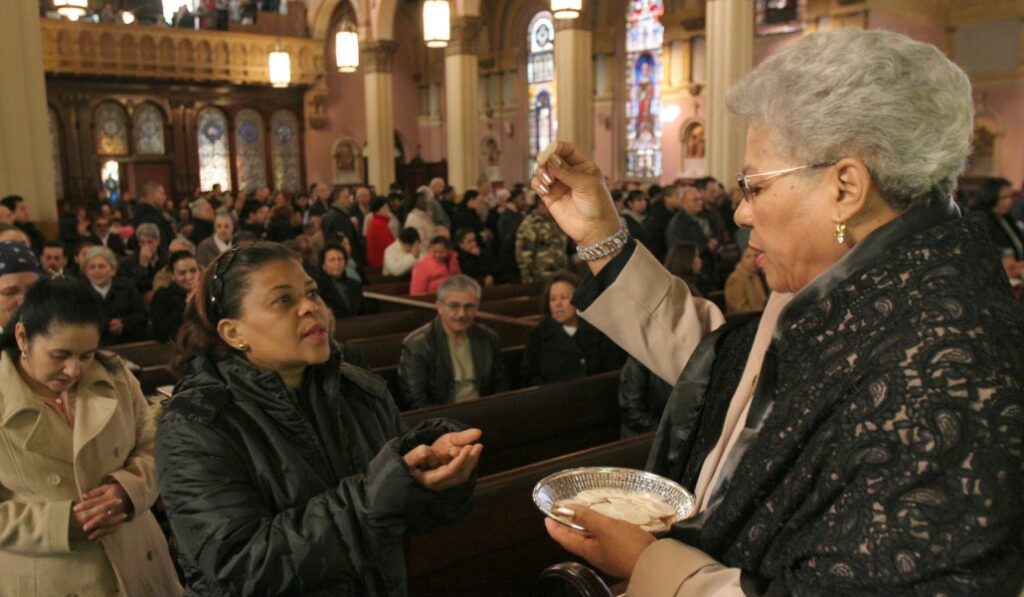 Una mujer distribuye la comunión durante una Misa.