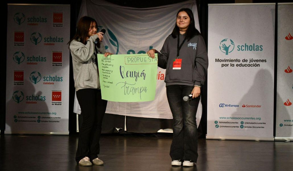 Dos chicas salen a un escenario a compartir su iniciativa de «reuniones trampa».