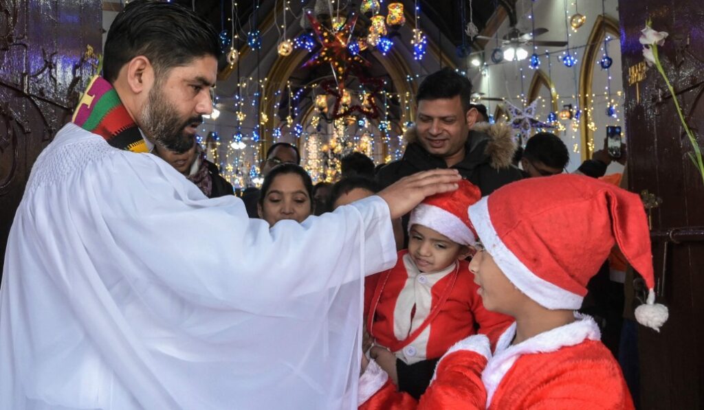 Un sacerdote bendice a niños vestidos de san Nicolás. Foto: AFP / Narinder Nanu.