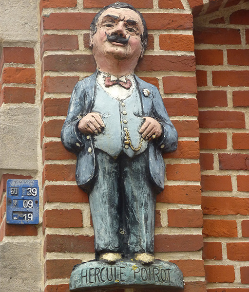 Escultura de Hércules Poirot en una fachada del pueblo belga de Ellezelles.