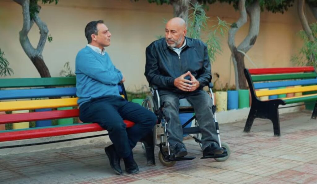 El sacerdote Mario León Dorado con un local que quedó en silla de ruedas y ahora apoya a jóvenes.