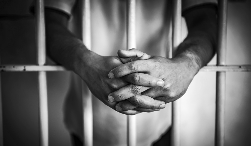 Foto de recurso en blanco y negro de un preso tras las rejas de una cárcel