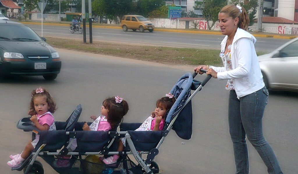 Foto de recurso de una madre con un carrito de trillizas