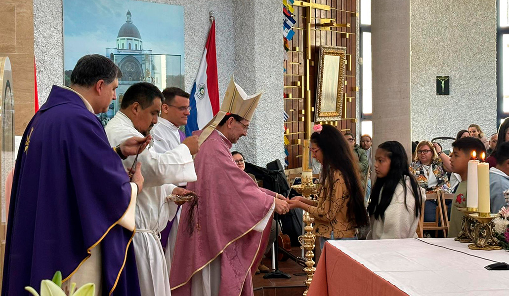 El arzobispo entrega una cruz a los niños que harán la Primera Comunión.
