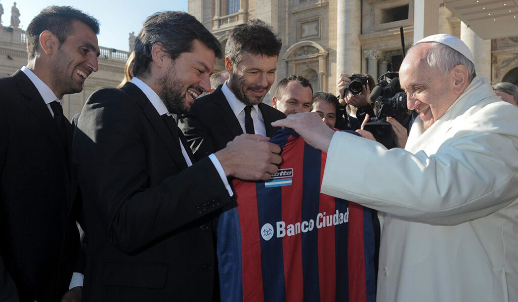 El Papa Francisco sostiene una camiseta del equipo de fútbol argentino San Lorenzo, que le regalaron los miembros del equipo, durante su audiencia general en la plaza de San Pedro en el Vaticano el 18 de diciembre de 2013.