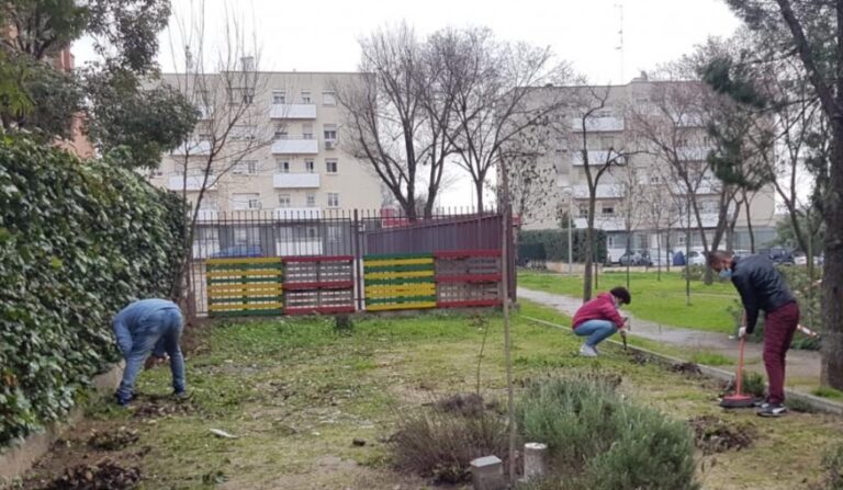 Personas atendidas por CEDIA trabajan limpiando un jardín anexo. Foto: Cáritas Madrid.